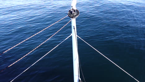 Close up shot of the pulpit and bow of a sail boat sailing over calm sea