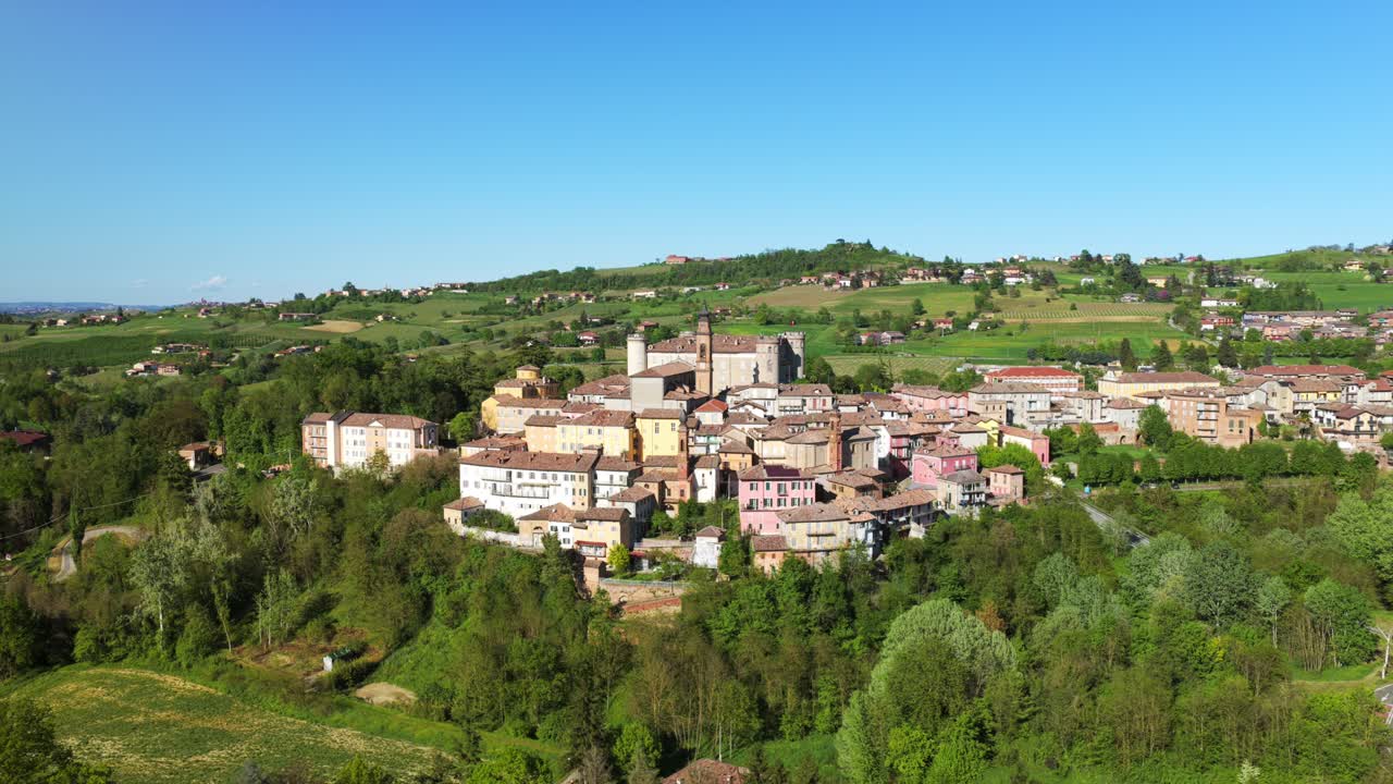 Costigliole d'Asti, historic Italian hilltop village with castle, surrounded by lush green landscape, Piedmont, sunny day, travel in Italy. Aerial drone panoramic view, copy space