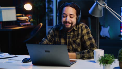 Hombre-Alegre-Relajándose-En-Casa-Viendo-Un-Programa-De-Televisión-En-Una-Computadora-Portátil-Usando-Auriculares