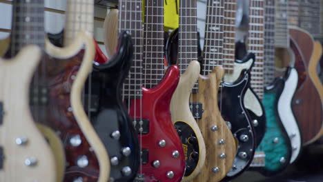 assortment of hanging guitars for sale in shop, pan across, wide