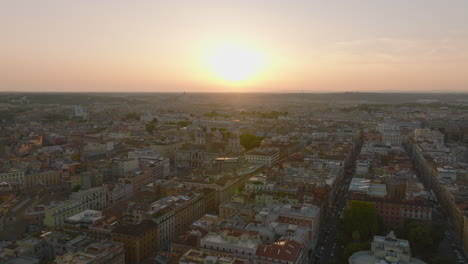 Aerial-ascending-footage-of-buildings-in-large-city-against-romantic-sunset-sky.-Historic-landmarks-between-residential-houses.-Rome,-Italy