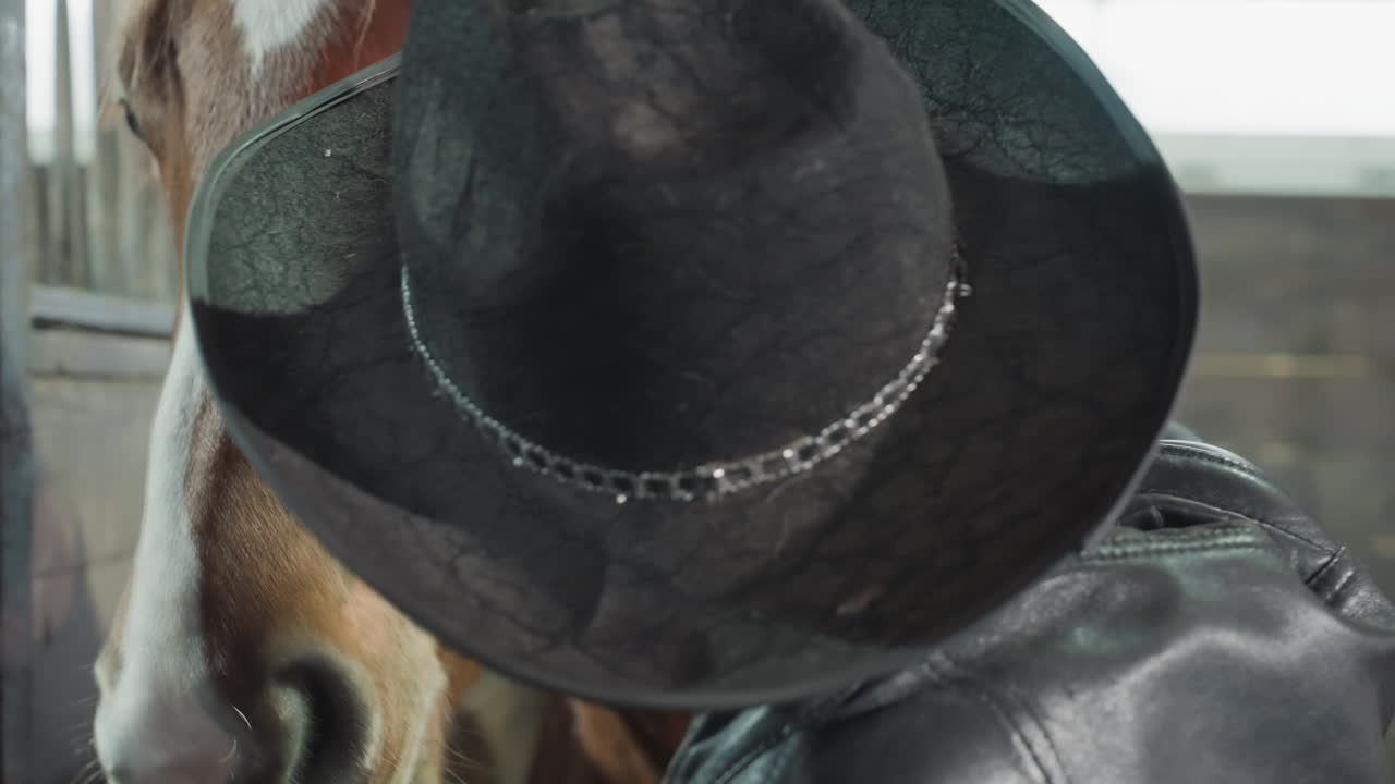 Cura equina delicata. Cowboy calma il cavallo con tranquillità. Momento di fiducia tra cowboy e cavallo. Scena pacifica di un cavallo che viene dolcemente confortato. Cowboy accarezza dolcemente il suo cavallo in un ambiente rustico di fienile