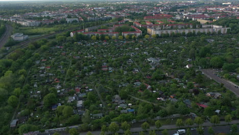 Fliegen-Sie-über-Gemeinschaftsgärten,-Die-Von-Eisenbahnschienen-Und-Reihen-Von-Wohngebäuden-Umgeben-Sind.-Luftaufnahme-Von-Kleinen-Häusern-In-Grüner-Vegetation.-Berlin,-Deutschland