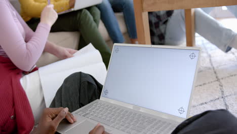 Diverse-group-of-teenage-friends-on-couch-and-using-laptop-with-copy-space-at-home,-slow-motion