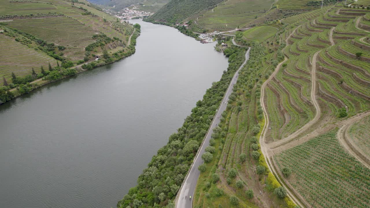 Vista aerea di ciclisti su una strada tortuosa lungo il fiume Douro e vigneti terrazzati in Portogallo