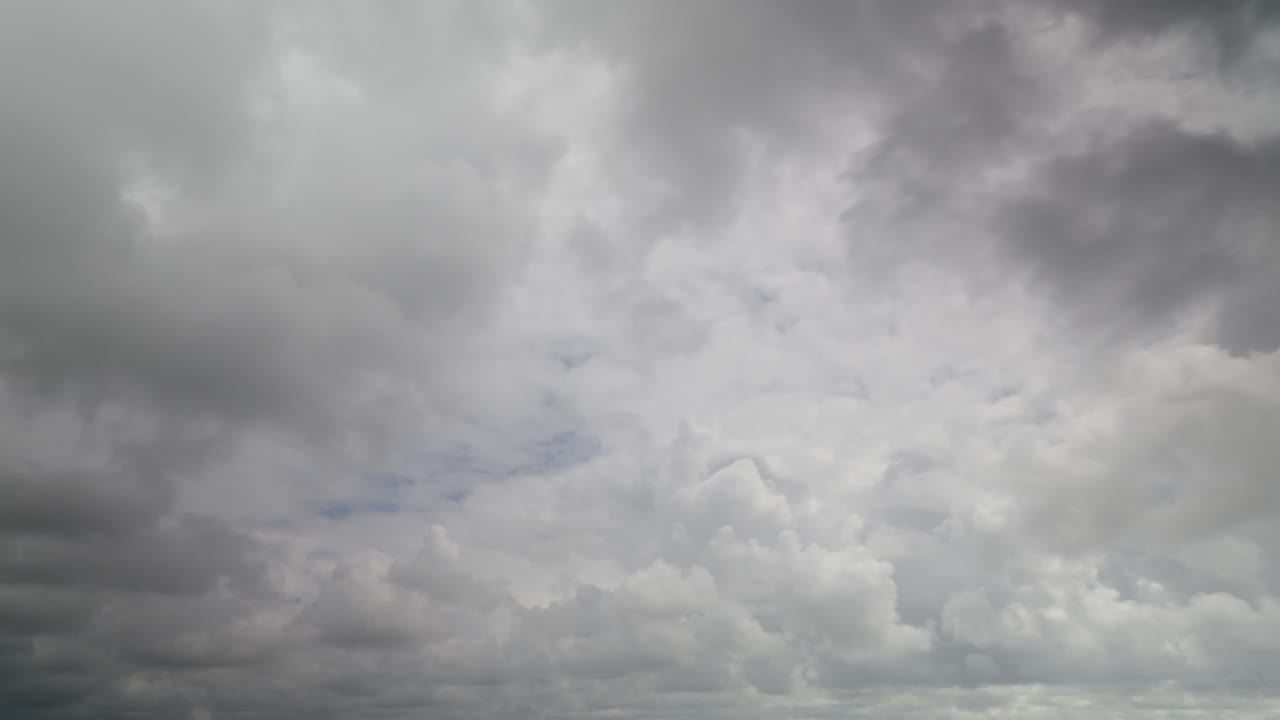 Grey storm clouds racing away from camera with small patches of blue sky, 30x time lapse