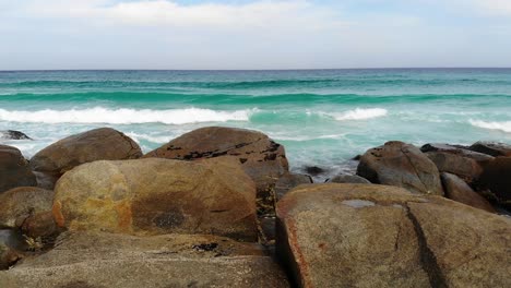 aerial reverse view revealing rocks at a beach in cloudy australia