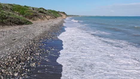 waves splash onto long stone beach in the dominican republic, dolly forward