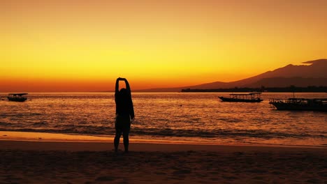 girl with outstretched hands admiring majestic golden sunset over the tropical sandy beach