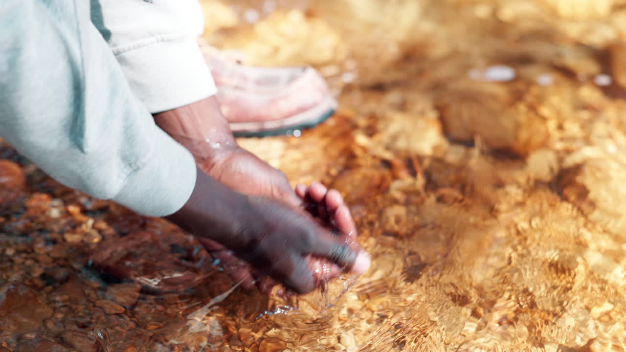 Hands cupping and playing with water in a stream