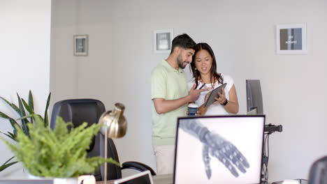 discussing project, colleagues using tablet and computer in modern office setting