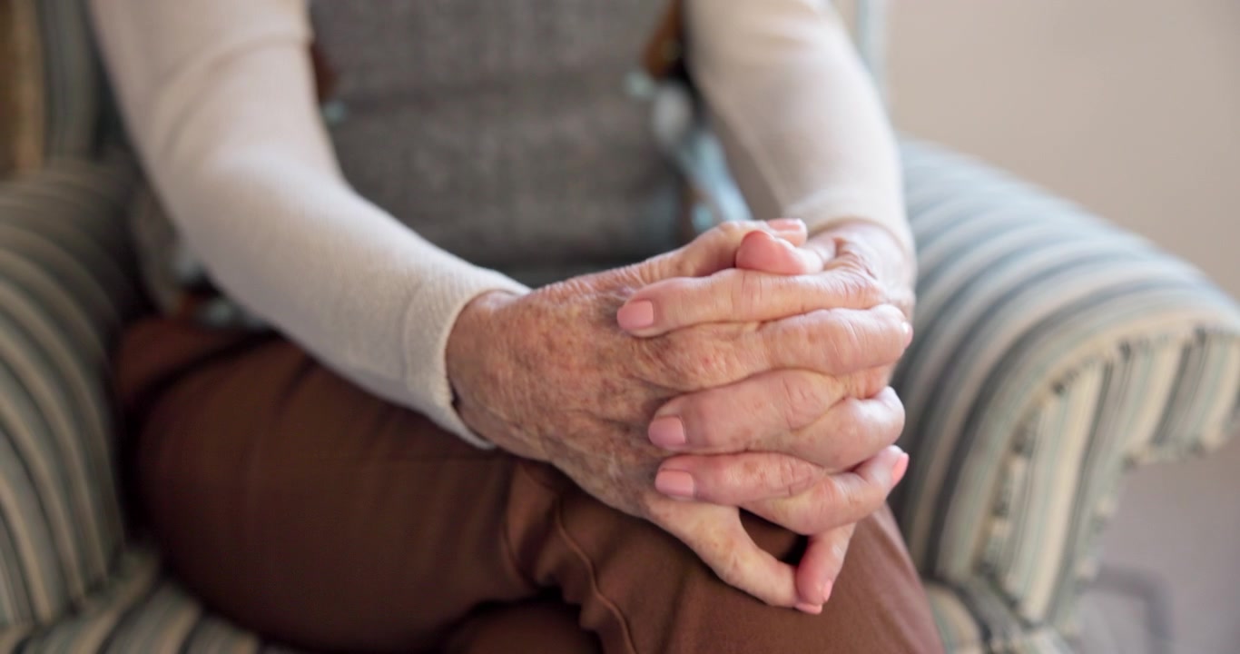 Primo piano di una donna anziana con le mani appoggiate in grembo