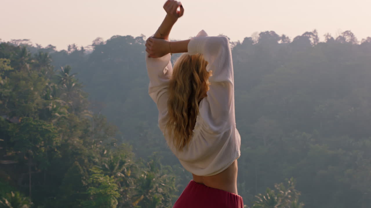 mujer viajera celebrando con los brazos levantados mirando la selva tropical al amanecer sintiendo alegría en las vacaciones de verano aventura disfrutando de un nuevo día en el paraíso
