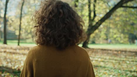 caucasian woman walking in the autumn park and turning to camera side.