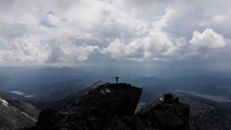 un hombre está de pie en la cima de una montaña.