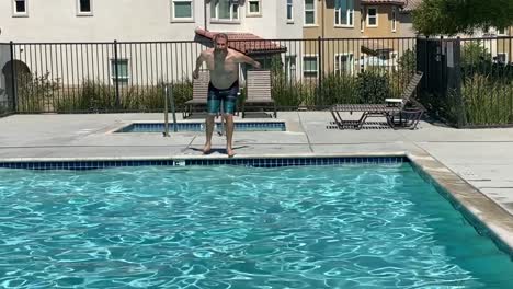 caucasian man jumping into community pool on a hot summer day