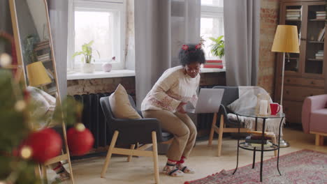 african american woman in christmas headband using laptop at home