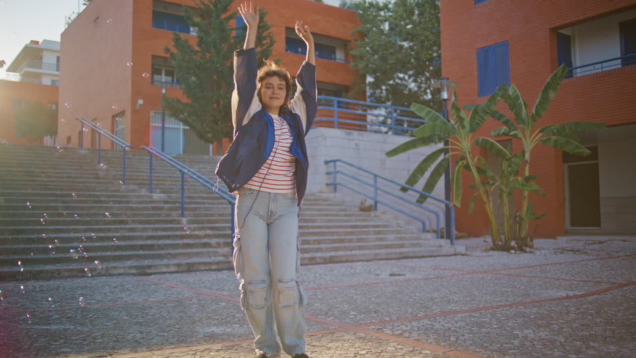 adolescentes informales bailando en la calle disfrutando de burbujas voladoras en la noche de verano.