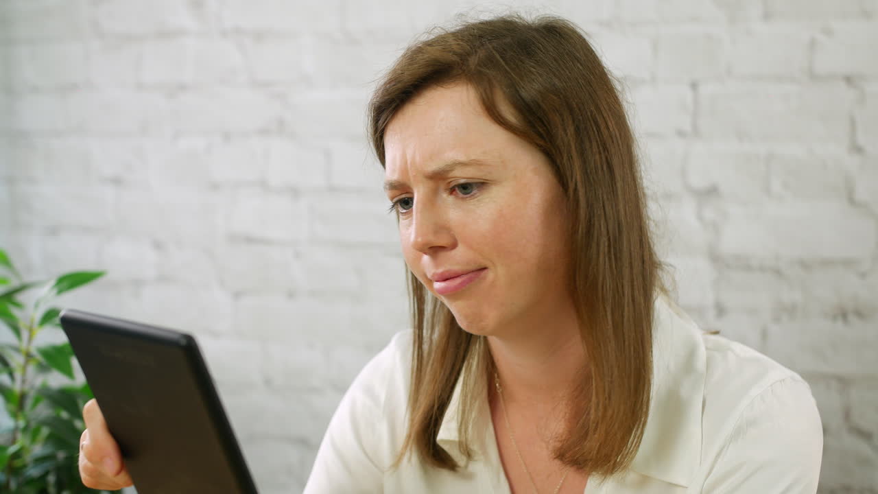 una mujer joven frustrada y triste usando una tableta trabajando en una oficina