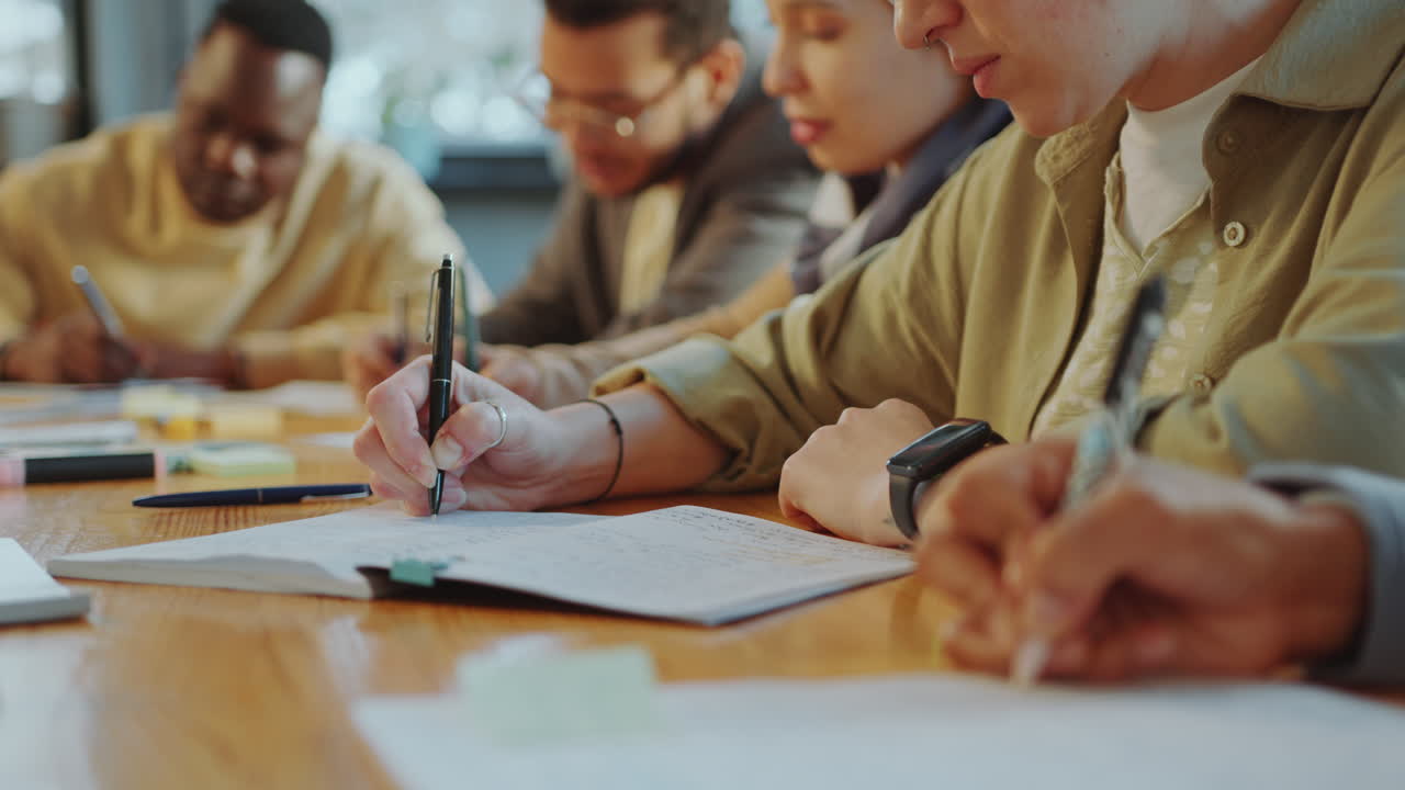Students Writing in Copybooks at Classroom Desk during Lecture