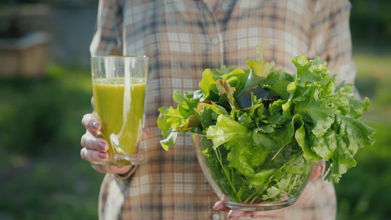 한 여자가 녹색 스무디 한 잔과 상추 한 접시를 들고 있다