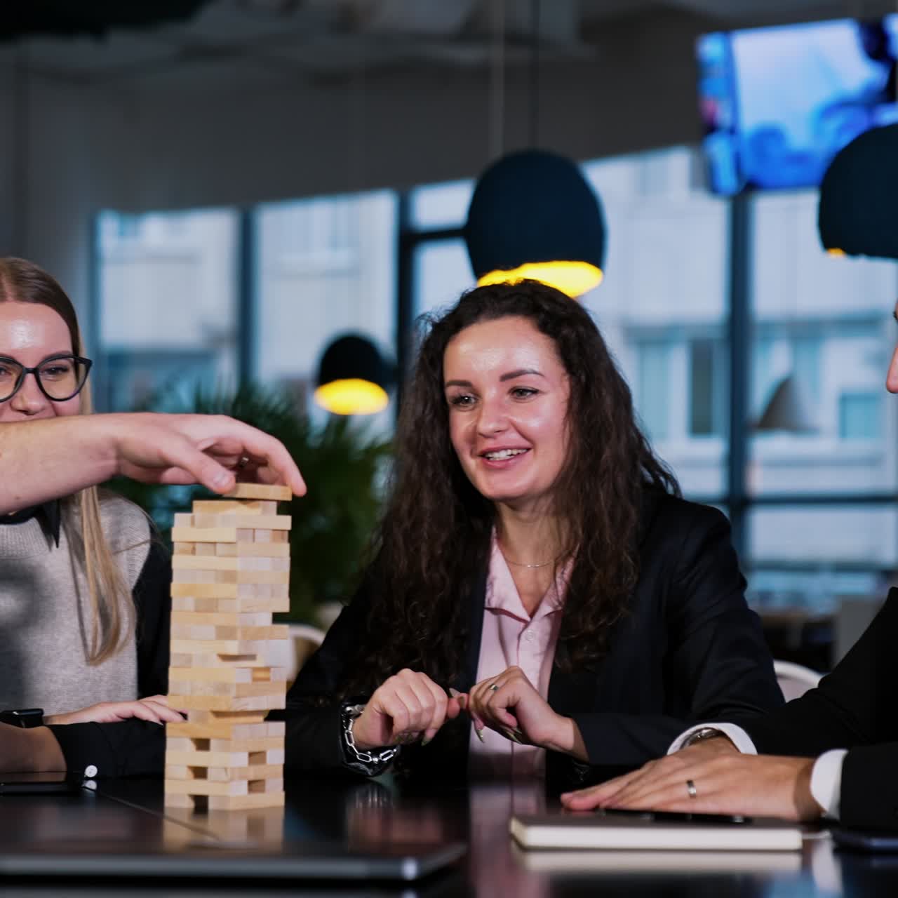 Friendly cheerful company playing game for pleasure. Leisure time spending playing jenga. People take turns to pull the wooden brick