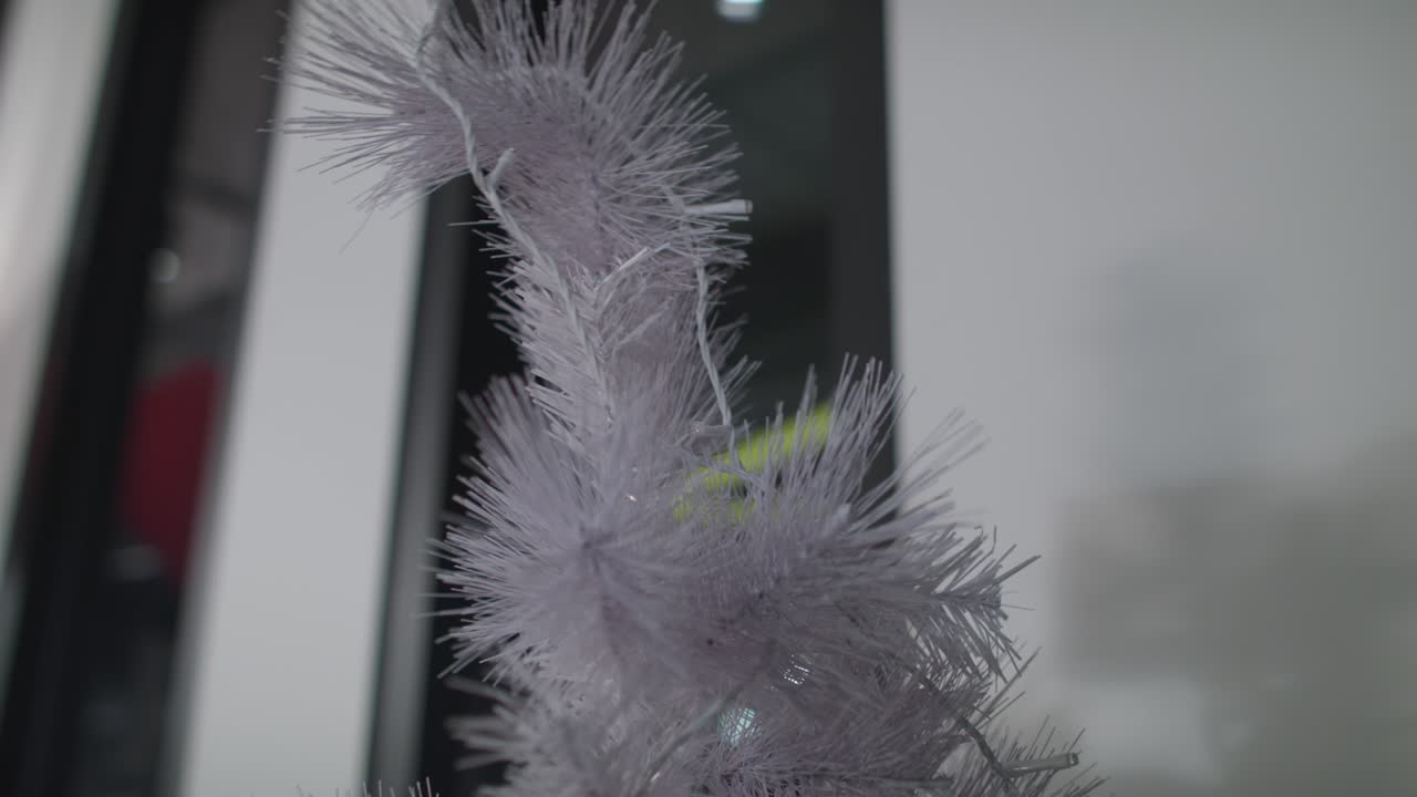 decorando un increíble árbol de navidad blanco con luces claras.