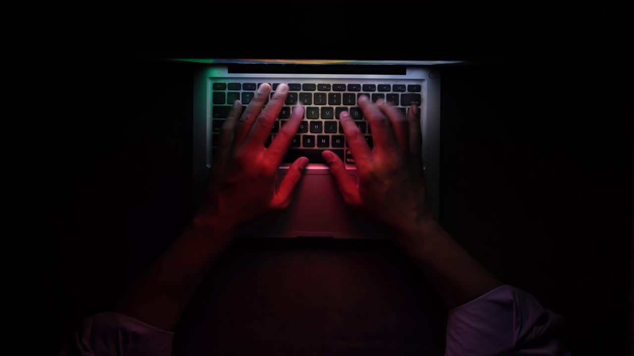 pessoa a digitar no portátil à noite
