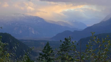 dramatic sunrise sky over the stawamus chief mountain and squamish river in british columbia, canada with forest trees in foreground