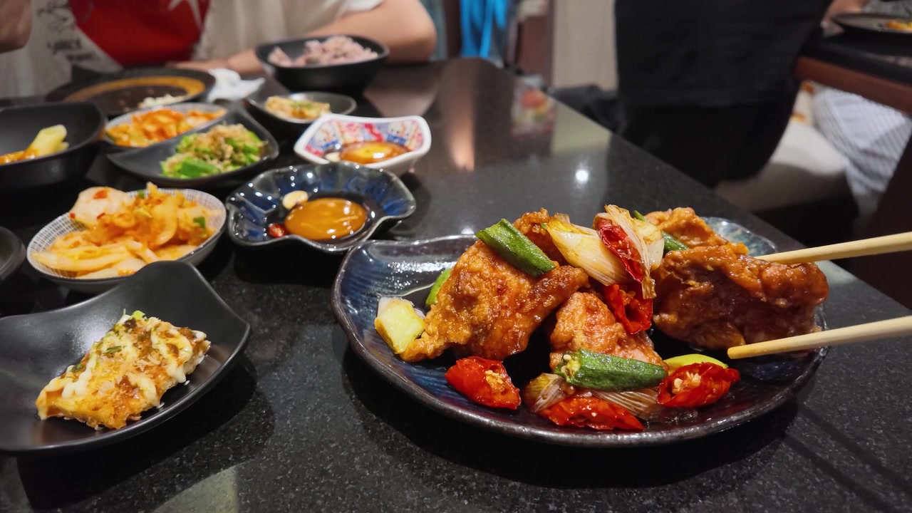 Sumpit mengambil ayam goreng pedas dari piring dengan okra dan cabai di Bangkok
