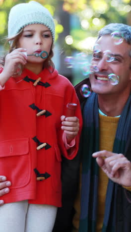 padre e hija soplando burbujas