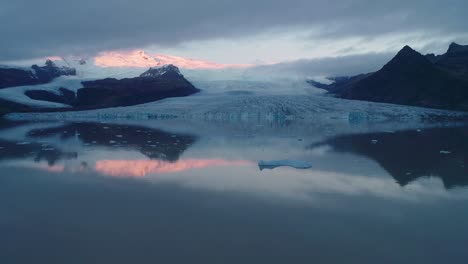 Imágenes-De-Drones-De-Fjallsárlón,-Islandia,-Que-Abarcan-Una-Amplia-Vista-Con-El-Flujo-De-Hielo-En-El-Agua-Durante-Un-Tranquilo-Amanecer-De-Otoño