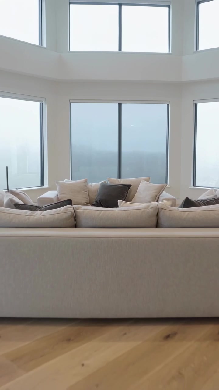 Vertical video: Pulling back camera revealing sofa and windows, showing room layout