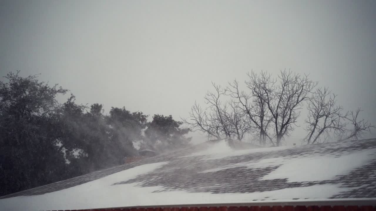 Heavy snow blowing across roof of a house.