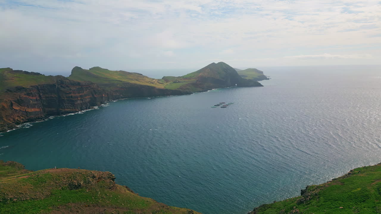 Calm ocean washing bay drone view. Serene green fields on cloudy morning aerial