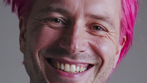primer plano de un hombre sonriente con cabello rosa