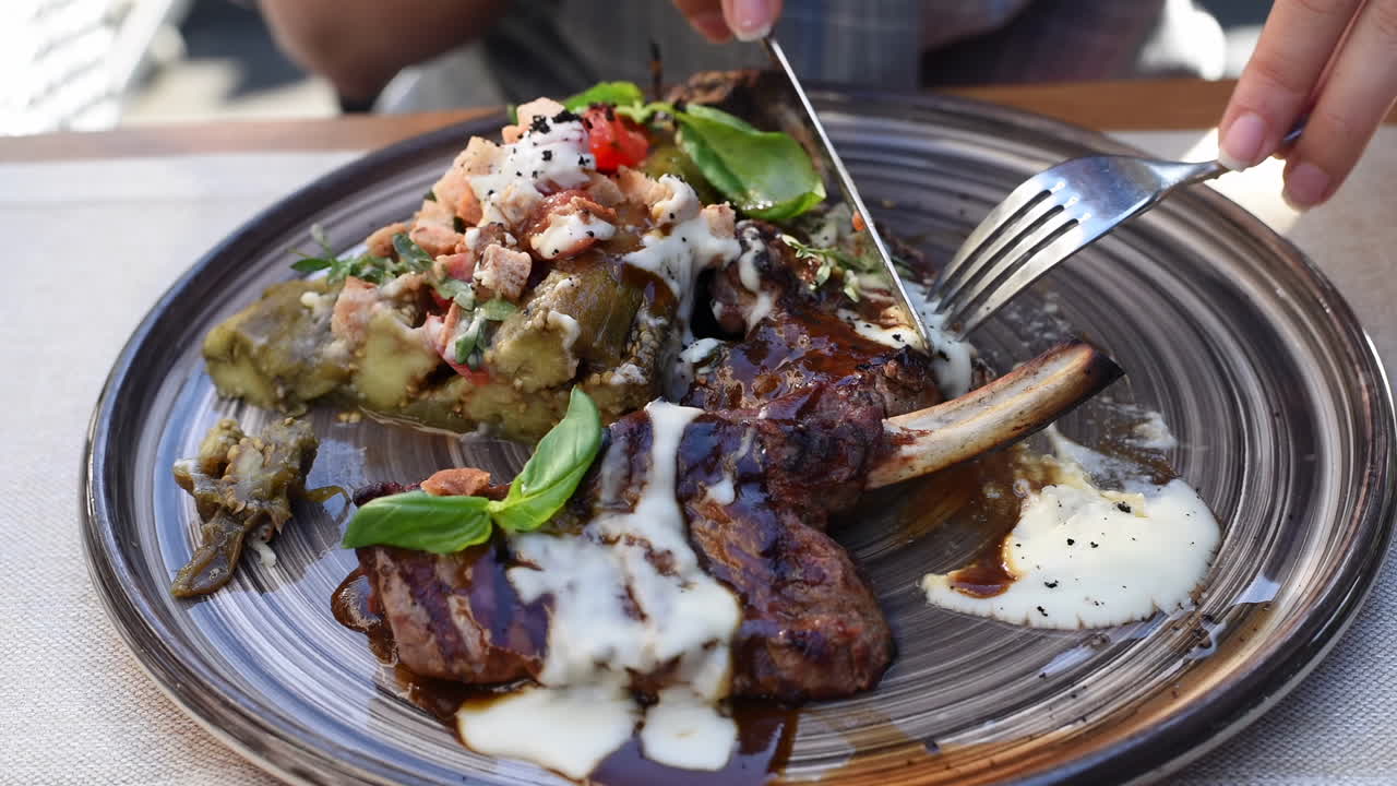 Close up of a woman eating ribs with vegetables at a terrace