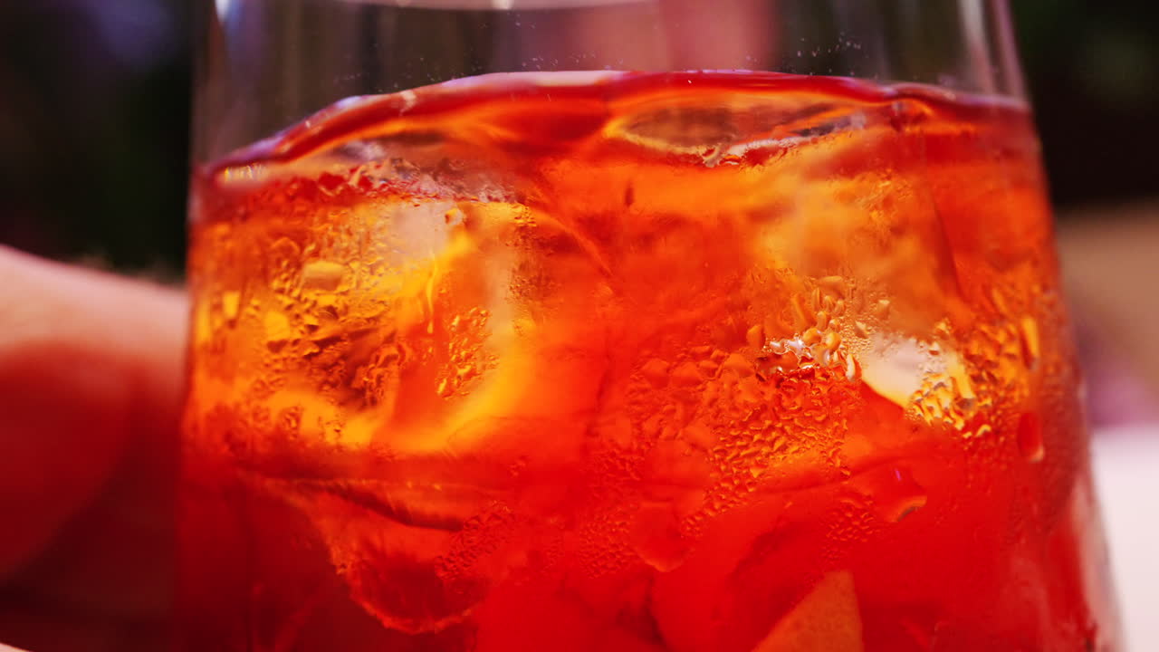 Primo piano macro dettagliato di un cocktail rinfrescante con cubetti di ghiaccio e goccioline d'acqua sulla superficie del bicchiere