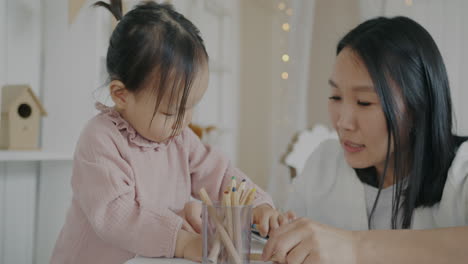 toddler and mother coloring together