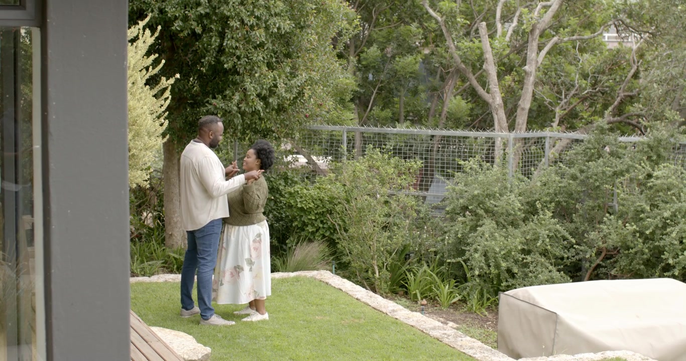 African couple standing yard, man proposing with ring while holding hands, embracing, copy space