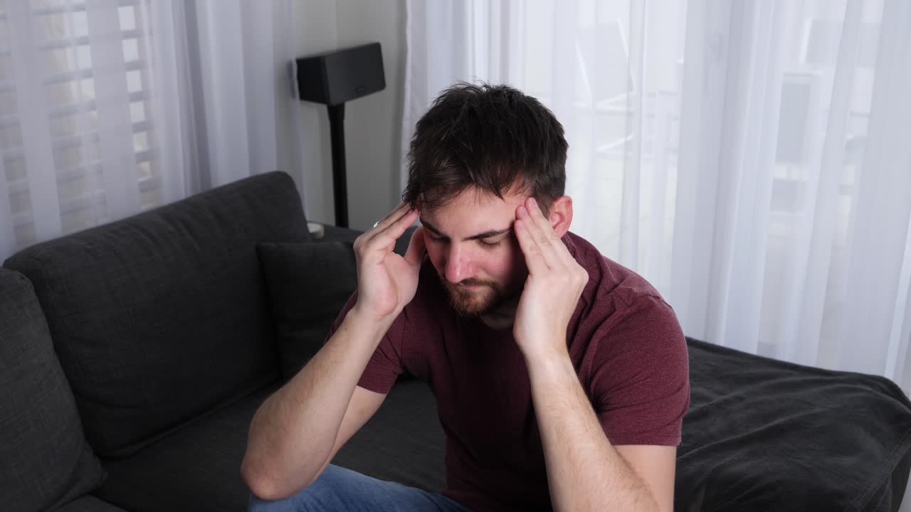 joven caucásico masajeando su cabeza para deshacerse del dolor de cabeza, migraña