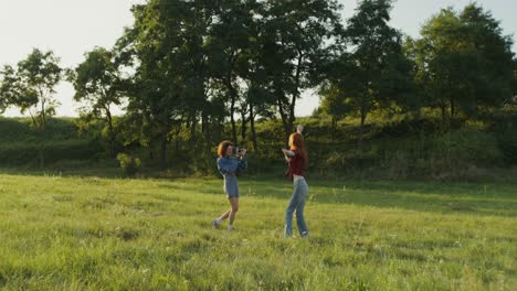 two women taking pictures in a field