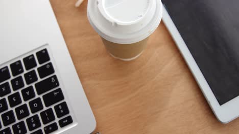 close-up of spectacle, disposable coffee cup with laptop and digital tablet on desk