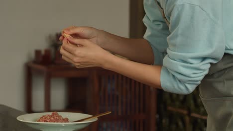 chef femenina rellenando albóndigas con carne de cerdo, productos de panadería caseros