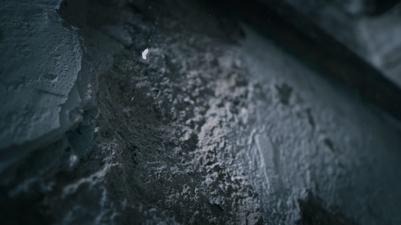 Rough wall texture revealed in blue backlight within underground room. low light background suited for crime, mystery, or horror settings