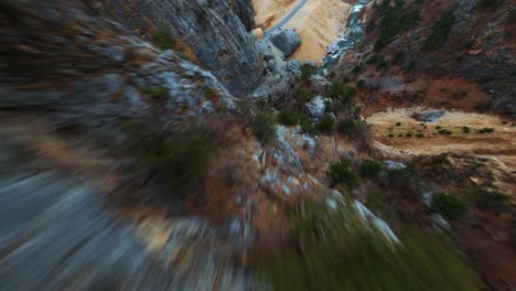 dron cinemático 4k fpv volando desde una montaña, hacia un arroyo