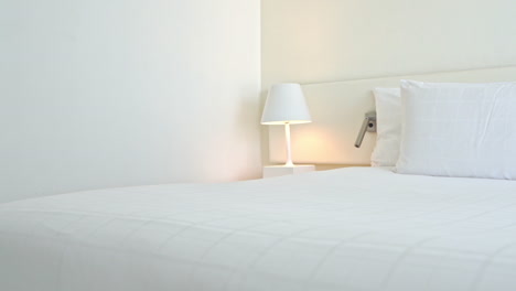 Panorámica-Sobre-Una-Cama-Blanca-En-Una-Habitación-De-Hotel-Muy-Blanca