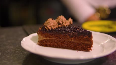 incredible shot of chocolate cake served by waitress standing by on a white plate in restaurant