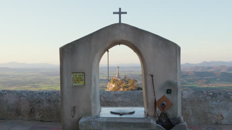 view from the monastery of san salvador, mallorca, overlooking a hill with a cross and mountains in the background