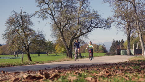 cycling couple enjoying a ride at the park in the autumn season, wide shot